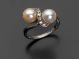 une bague en perles blanches et diamants sur une surface noire