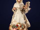 une figurine ancienne représentant une femme vêtue d'une robe blanche et tenant un oiseau