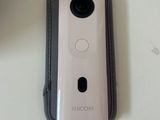 a white camera sitting on a table next to a cell phone