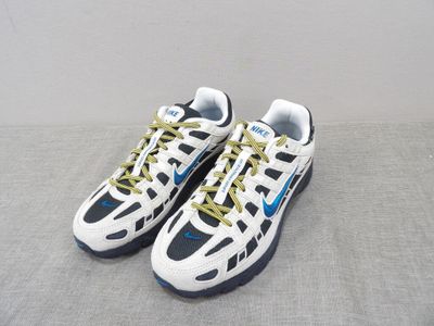 pair of white and blue sneakers with yellow laces on a gray surface