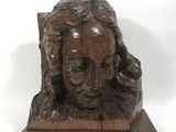 bronze sculpture of a woman ' s head on a wooden base