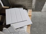 une pile de carreaux blancs posée sur une palette, à côté d'une pile de cartons