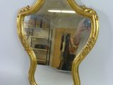 un miroir accroché au mur, avec un cadre doré