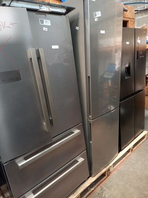 Plusieurs réfrigérateurs et congélateurs sont empilés sur des palettes dans un entrepôt