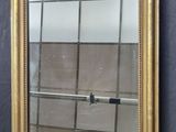 an image of a gold framed mirror hanging on a wall