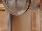 a silver clock sitting on top of a glass block