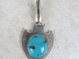 silver and turquoise turquoise stone pendant on a white background