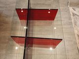 a glass table with a red shelf on it in the middle of a room