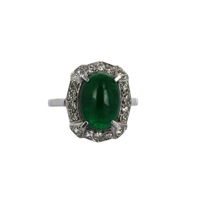 gros plan d'une bague avec une pierre verte entourée de diamants