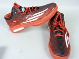adidas shoes with orange laces and black soles on a white surface