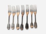 six forks are lined up in a row on a white surface