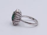 a close up of a ring on a white surface with a green stone