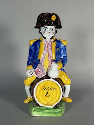une figurine représentant un homme assis sur un tonneau