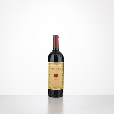 a bottle of wine sitting on top of a table next to a white wall