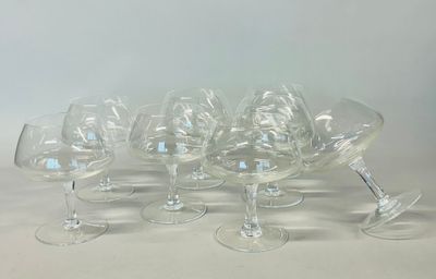 six clear wine glasses are lined up in a row on a white surface