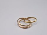 two gold wedding rings on a white surface
