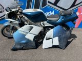 une moto bleue garée devant un mur recouvert de graffitis