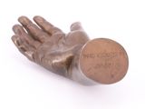 a bronze hand with a coin on it on a white surface