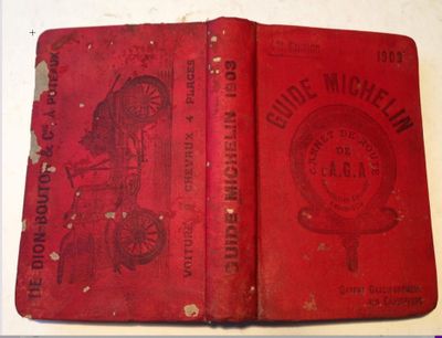 an old red book sitting on top of a table next to a clock