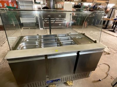 stainless steel counter top with three pans of food in a commercial kitchen