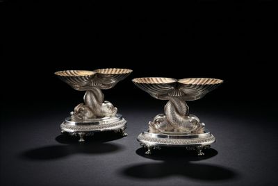 une paire de bougeoirs en argent sur des socles, sur fond noir