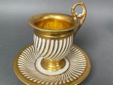 gold and white cup and saucer on a saucer on a gray surface