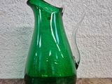 un pichet en verre vert posé sur une table en marbre