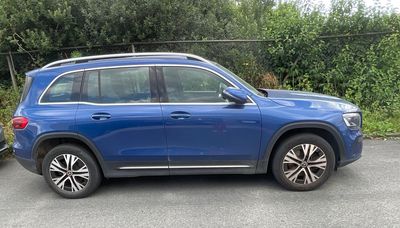 Le SUV bleu est garé sur un parking, à côté d'une voiture noire.