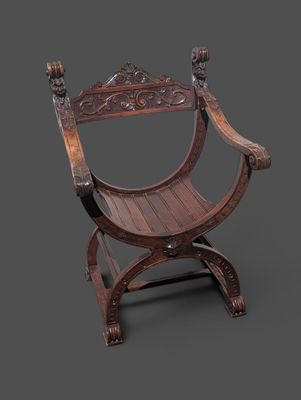 une vieille chaise en bois dont l'assise est sculptée, sur fond gris