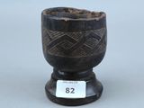 une vieille tasse en noir et blanc posée sur un socle en bois