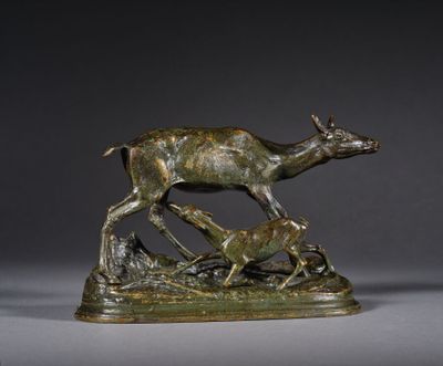 une statue en bronze représentant un cerf et deux biches dans un champ