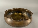 an old brass bowl sitting on top of a white surface