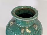 a green vase that is sitting on a white surface