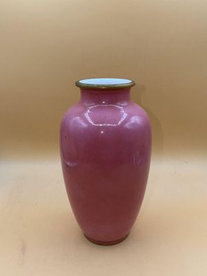 un vase violet posé sur une table, sur fond marron