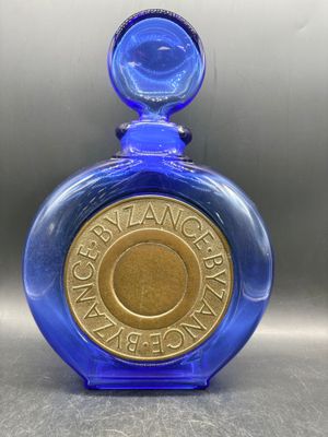 une image représentant une bouteille en verre bleue sur laquelle repose une pièce d'or