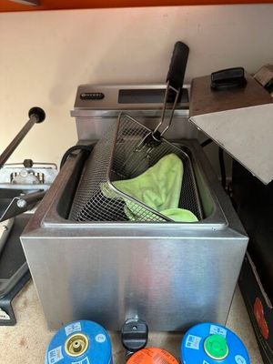 une photo d'une cuisine avec une friteuse et d'autres objets posés sur le plan de travail