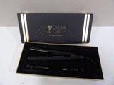 a black box with a gold trim and a black curling brush in it