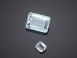 an aquamarinee and a diamond on a black surface