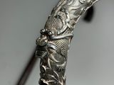 gros plan sur une canne en argent surmontée d'une tête de dragon