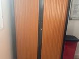 une armoire dans un coin de la pièce, à côté d'une poubelle rouge