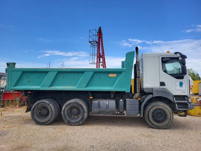 a green dump truck that is parked in the dirt