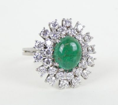 gros plan d'une bague avec une pierre verte entourée de diamants blancs