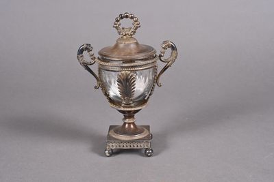 une coupe en argent avec un couvercle, posée sur un socle