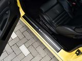 a yellow car with its door open on the side of the road