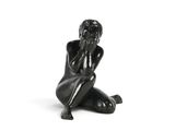 sculpture noire représentant une femme assise par terre, les mains sur le visage