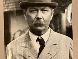 une photo en noir et blanc d'un homme en costume et chapeau