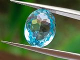un gros plan d'un cristal bleu tenu par une pince