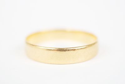 a close up of a gold wedding ring on a white surface