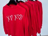three red shirts are hanging on a rack in front of a white wall