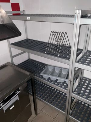 une cuisine équipée d'une cuisinière, d'un évier et d'étagères